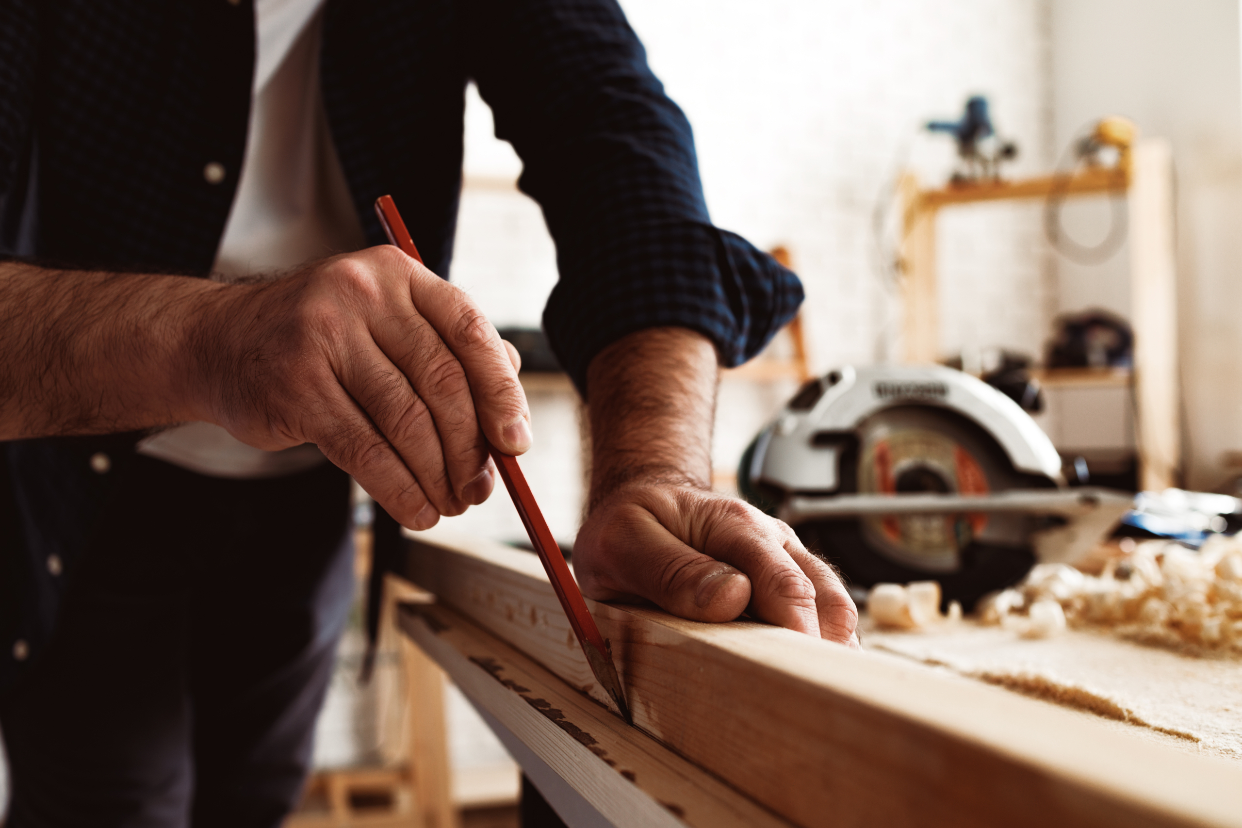 Artigiano pialla una tavola di legno al banco da lavoro in officina.