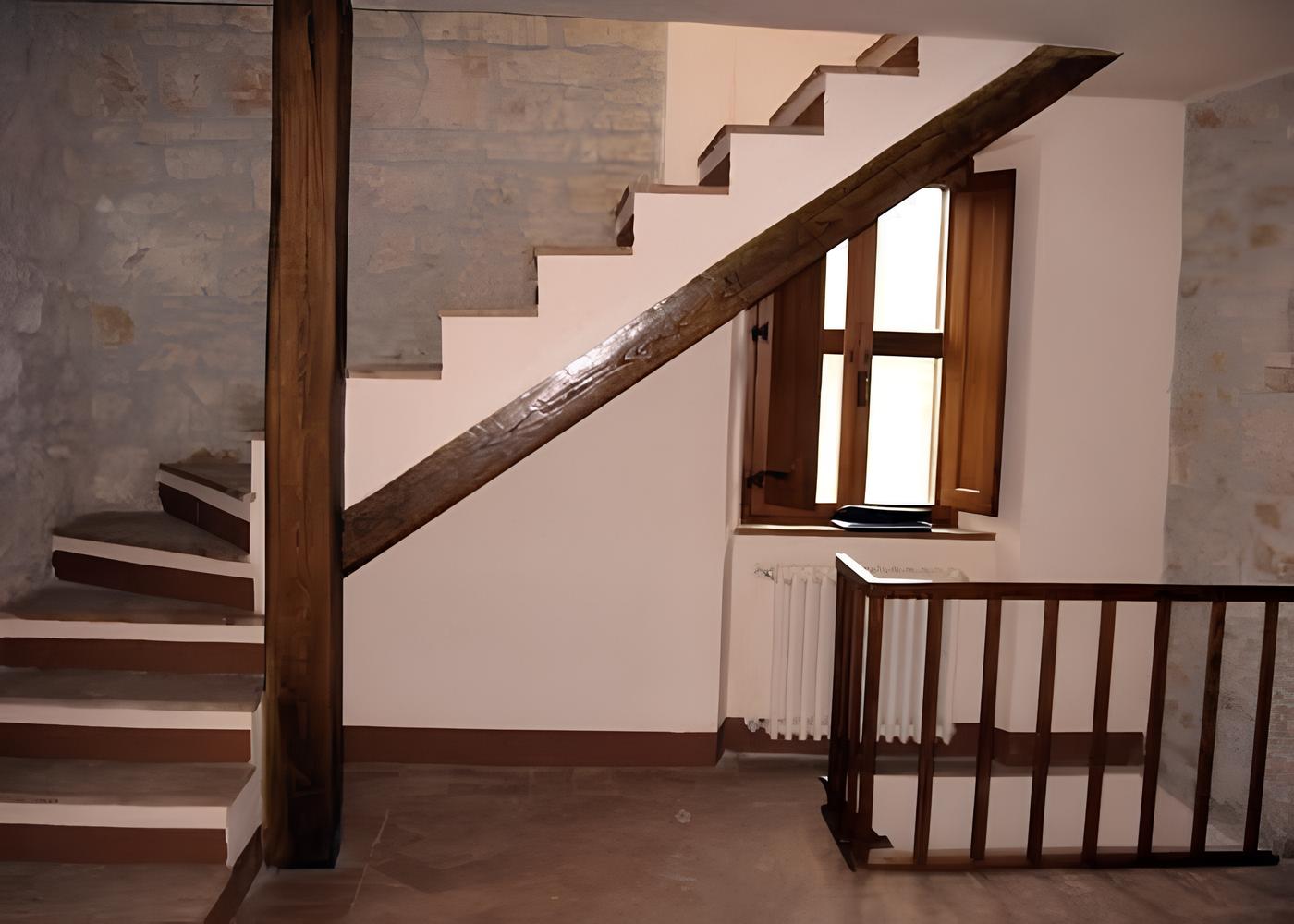 scale e tetto (1) Scala in legno con gradini in pietra e ringhiera in legno in un interno con pareti bianche e finestra.