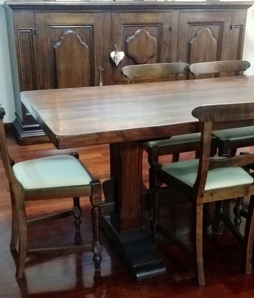 Tavolo in legno con piano in marmo chiaro e sedie in legno con sedute in tessuto chiaro, credenza in legno scuro sullo