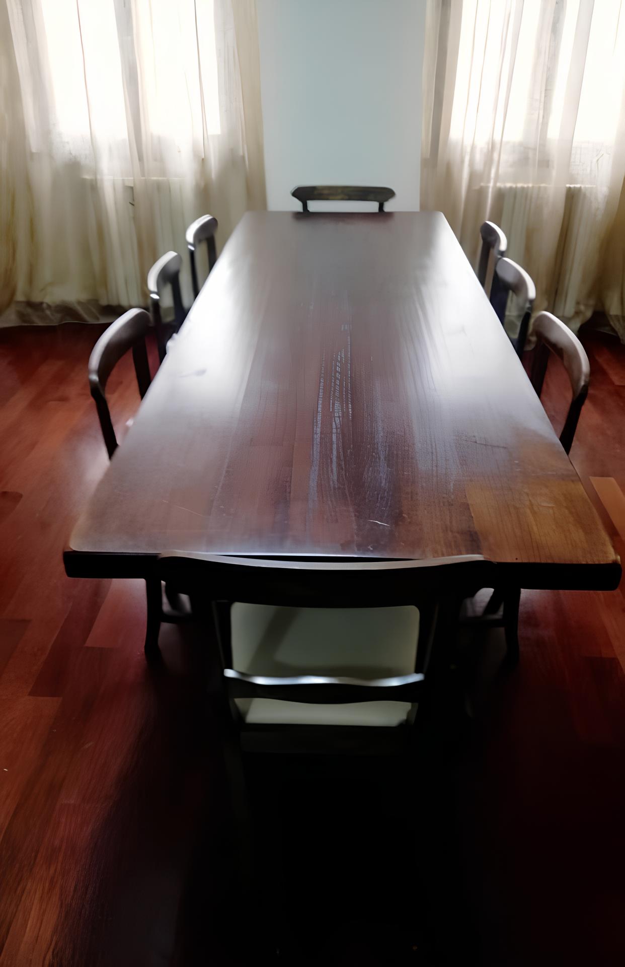 tavolo Tavolo da riunione in legno scuro con sei sedie nere in una sala con pareti azzurre e tende bianche.